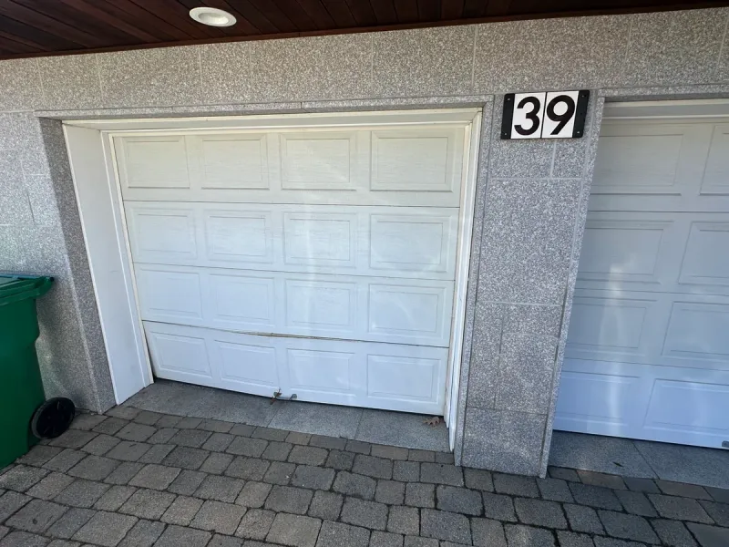 Garage door with damaged buckled bottom panel before repair